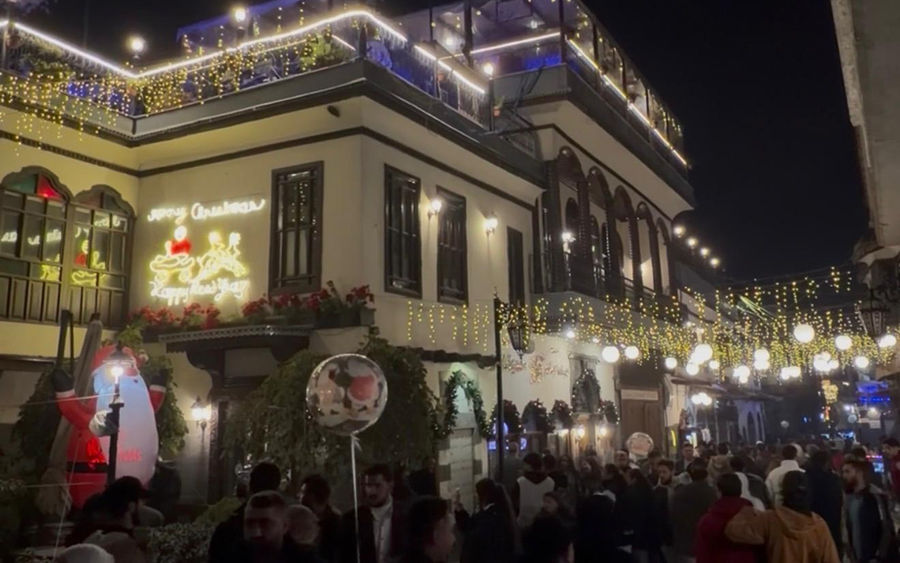 A crowded Damascus street lit up for Christmas at night
