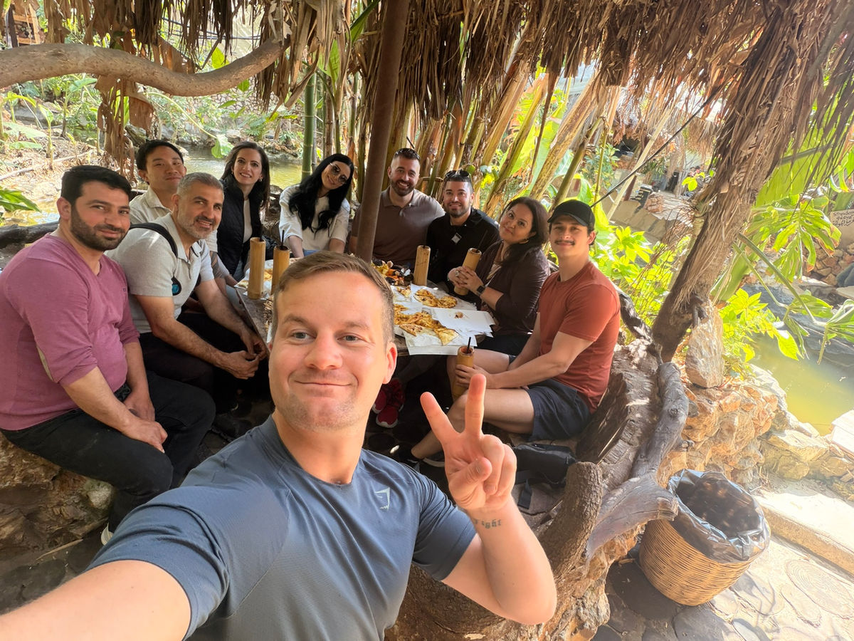 Group selfie at an outdoor lunch under the trees