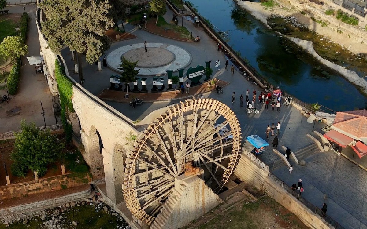 A giant wooden waterwheel beside the Orontes river in Hama, seen from above