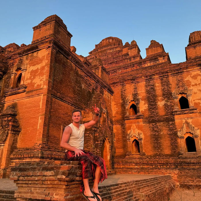 Nick sitting on the steps of red brick temples at sunset